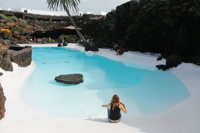 Woman in swimming pool by sea against sky