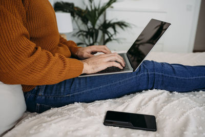 Hands of freelancer typing on laptop at home