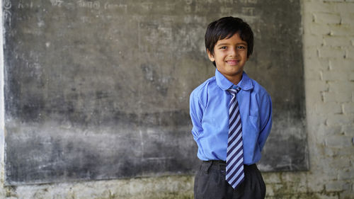 Portrait of happy indian school child sitting at desk in classroom, school kids