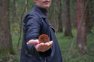 Midsection of man holding ice cream in forest