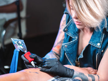 Close-up of tattooist making tattoo on customer