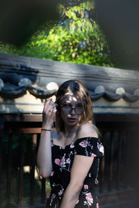 Portrait of beautiful young woman standing by wall outdoors