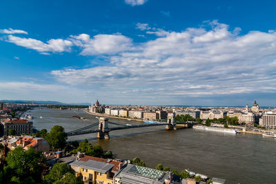 High angle view of bridge over river by buildings in city against sky