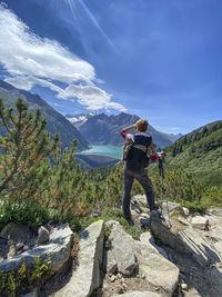 Rear view of a person overlooking the reservoir against mountain range and blue sky