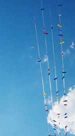 Low angle view of colorful clothespins against blue sky