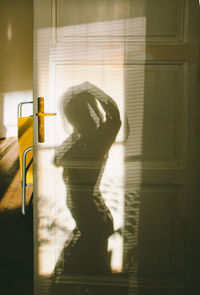 Side view of woman standing by window at home