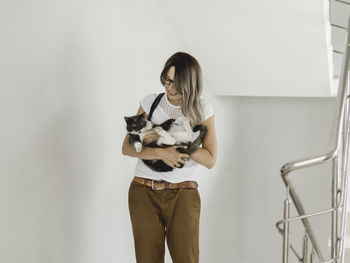 Smiling woman strokes stray cat on stairs. volunteer is saving undomestic animal. pet adoption.