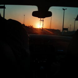 Silhouette man seen through car windshield during sunset