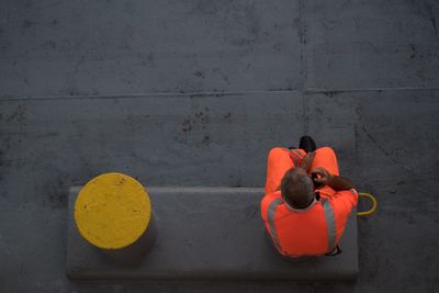 Manual worker talking on mobile phone while sitting at footpath