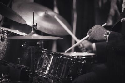 Midsection of man playing drum kit