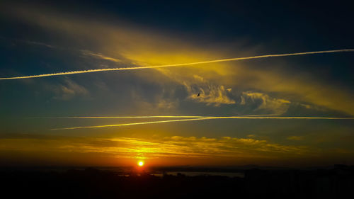 Low angle view of vapor trails in sky during sunset