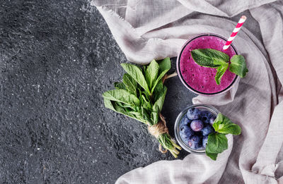 Directly above shot of blueberries and smoothie by mint leaves on rustic stone table