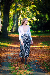 Full length of woman standing by tree in forest