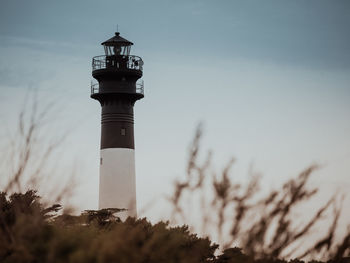 Lighthouse by sea against sky