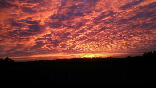 Silhouette landscape against dramatic sky during sunset