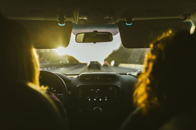 Rear view of female friends traveling in car during sunset