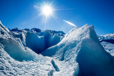 Scenic view of snowcapped mountains against blue sky