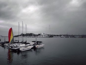 Boats in sea against cloudy sky