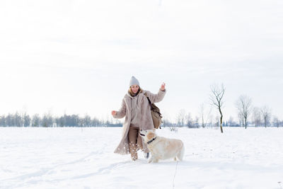 Young beautiful woman and her golden retriever dog having fun in winter.