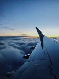 Airplane wing against sky during sunset