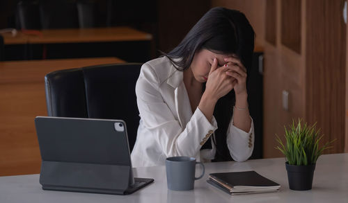 Midsection of woman using mobile phone while sitting on table
