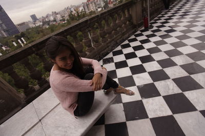 High angle portrait of woman sitting on tiled floor