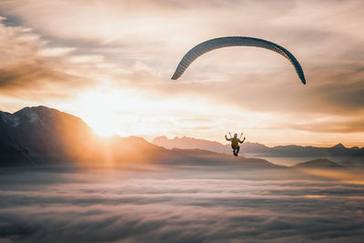 Person paragliding against sky during sunset