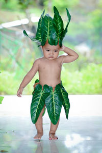 Cute boy wearing leaves and garland standing outdoors