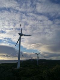 Low angle view of windmill on field against sky