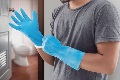 Midsection of mid adult man wearing gloves at home