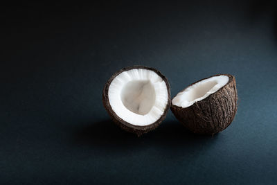 Two halves of coconut isolated on a black background with empty place for text