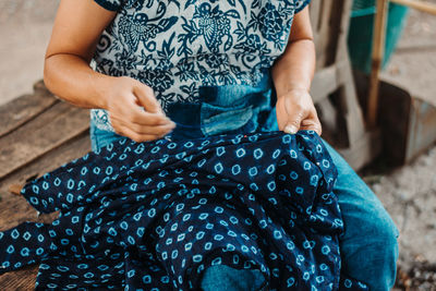 Midsection of woman sitting on sidewalk