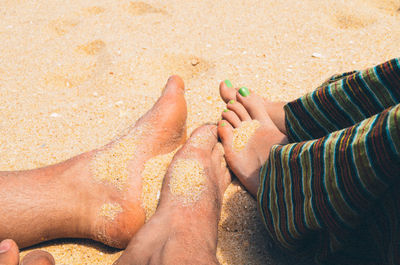 Low section of woman lying on sand at beach