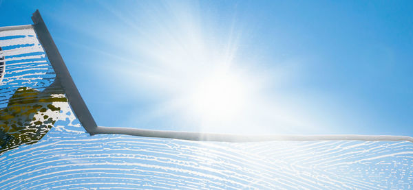 Low angle view of bright sun during winter against blue sky