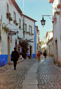 Rear view of people walking on street amidst buildings