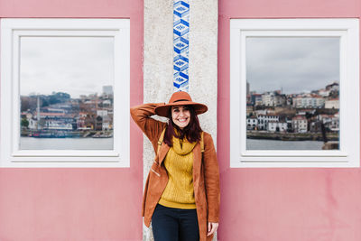 Woman standing by window against buildings in city