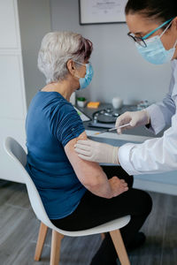 Midsection of doctor injecting patient in hospital