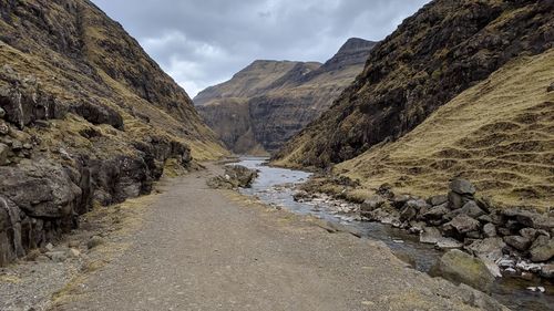 Scenic view of stream amidst mountains against sky