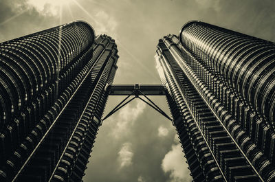 Low angle view of skyscrapers against cloudy sky