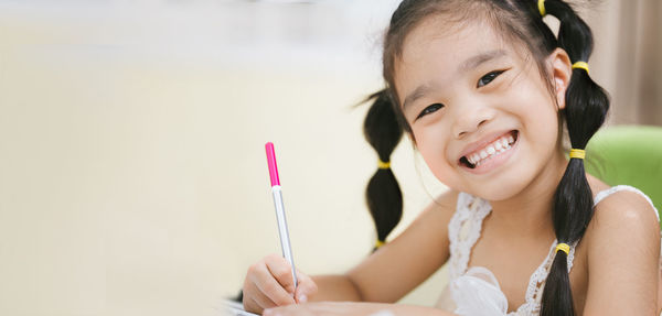 Close-up portrait of smiling girl sitting on table at home