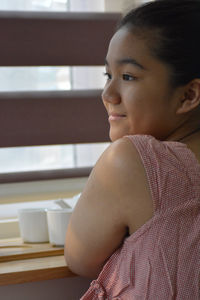 Portrait of young woman sitting on window