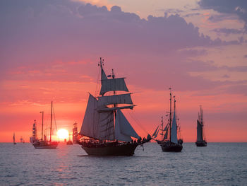 Silhouette of sailboats in sea against sunset sky