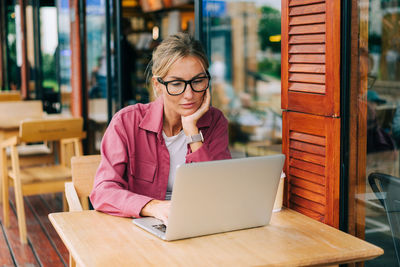 Young beautiful business woman working remotely on a laptop in a coffee shop.