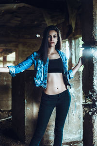 Portrait of beautiful young woman standing against wall