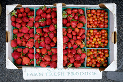 Directly above shot of strawberries and tomatoes in crate for sale at market