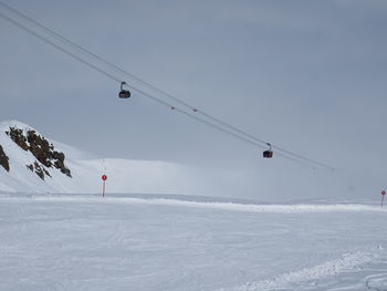 Overhead cable cars over snowcapped mountains against sky