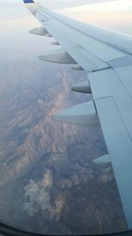 Cropped image of airplane wing over landscape