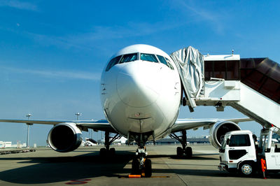 Front view of airplane on airport runway against sky