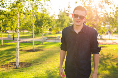 Portrait of young man wearing sunglasses standing against plants