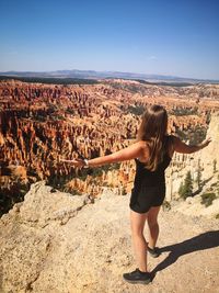 Full length of woman standing on rock against sky